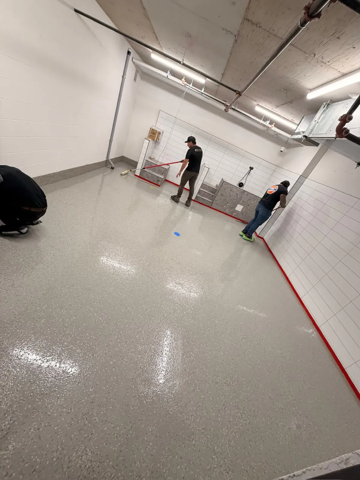 Flooring crew applying an epoxy coating in a commercial service area